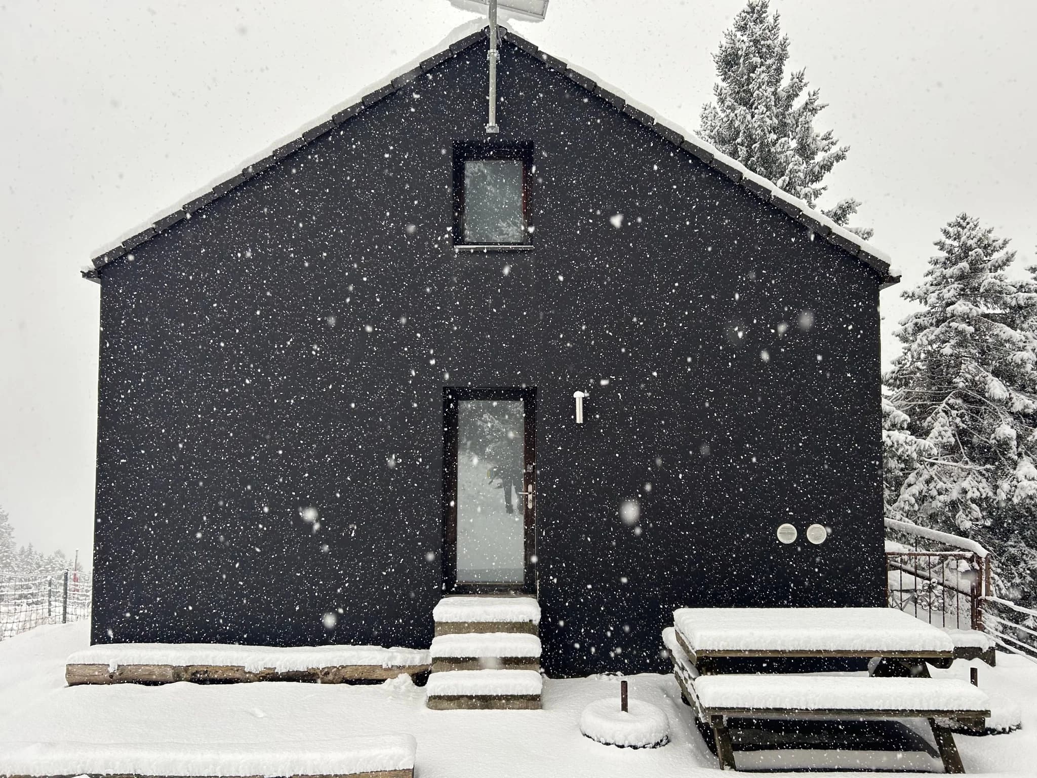 Black alpine house in falling snow