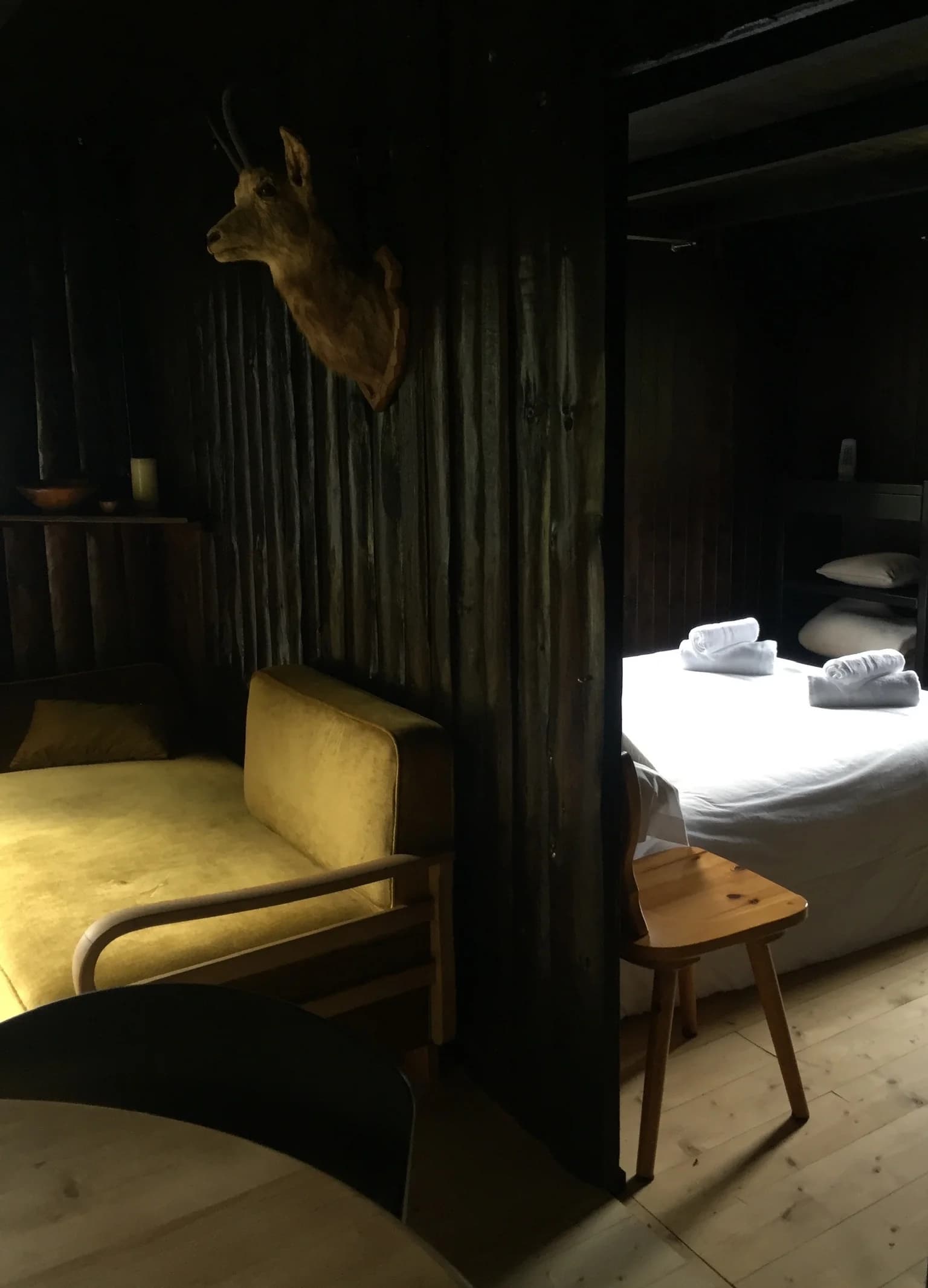 Bedroom suite with yellow lounge chair and dark wood partition