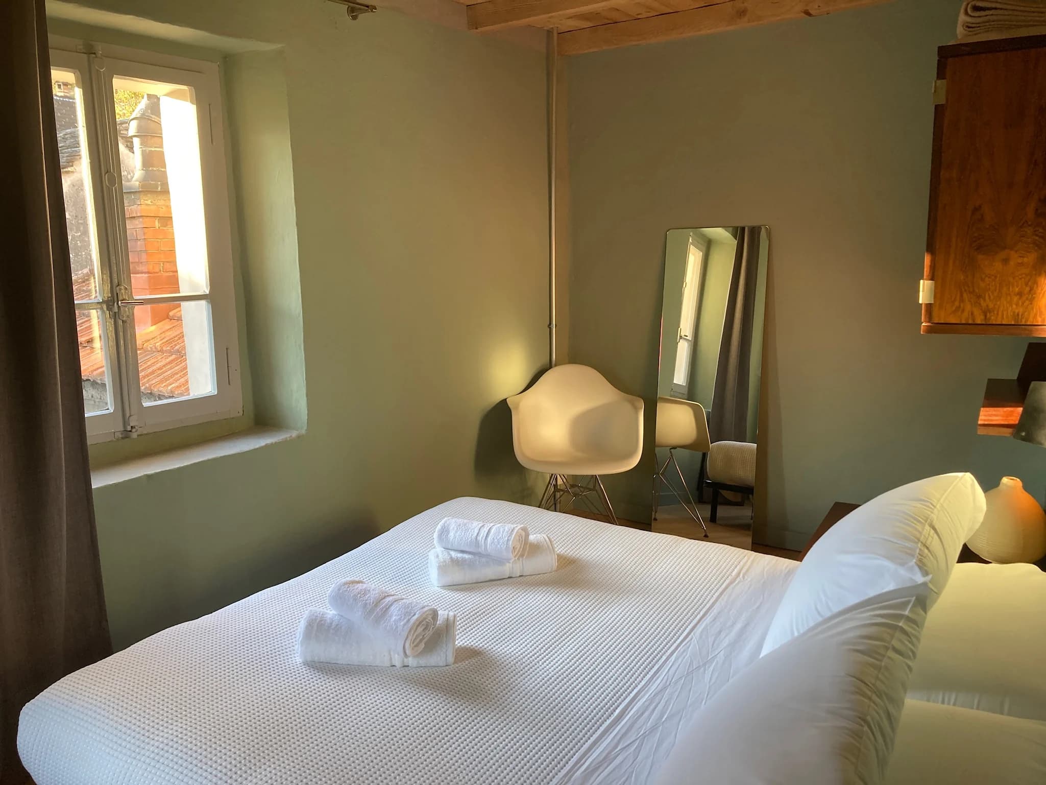 Sunlit bedroom with mirror and white linens
